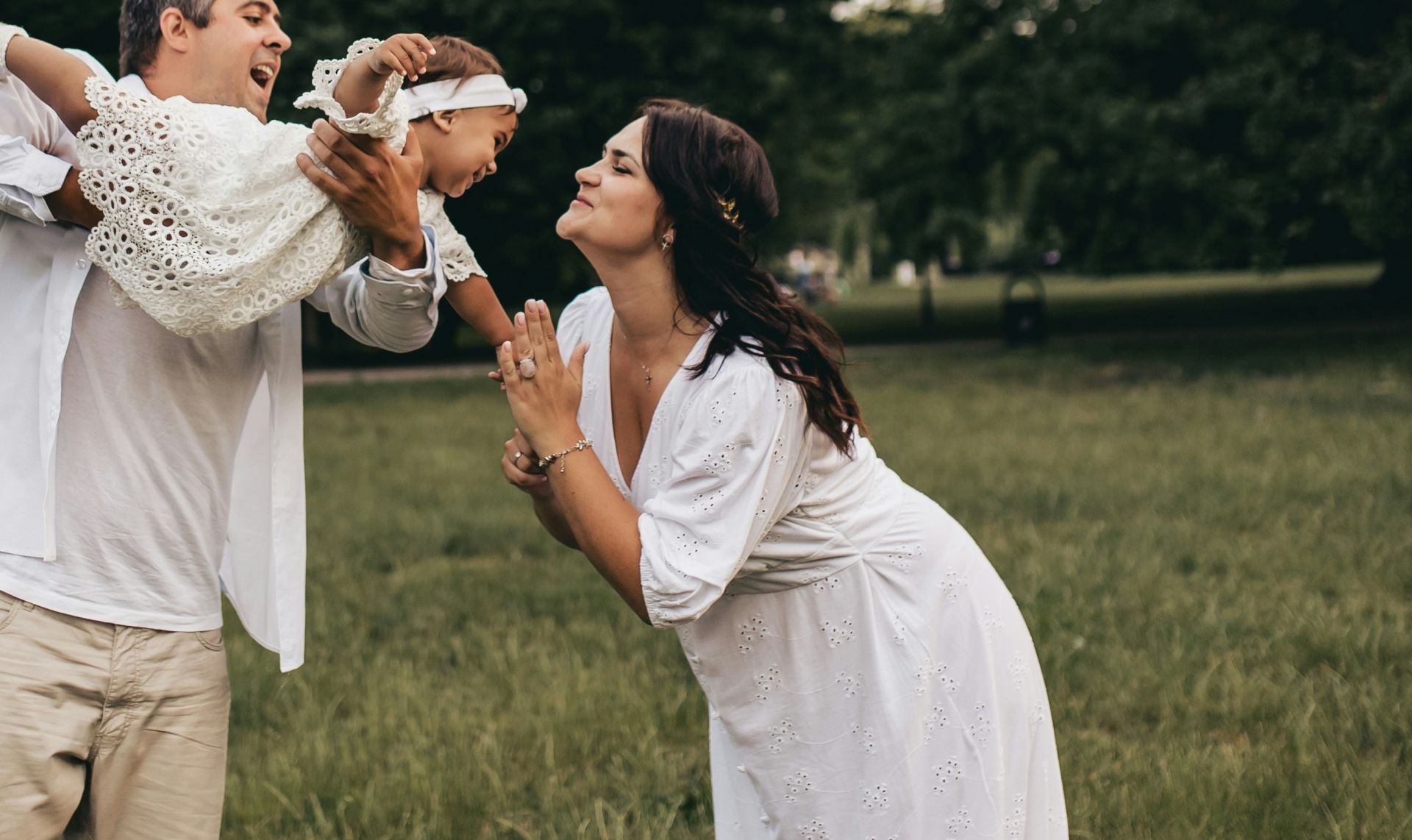 Family enjoying quality time outdoors under a tree, capturing smiles and joyful moments.